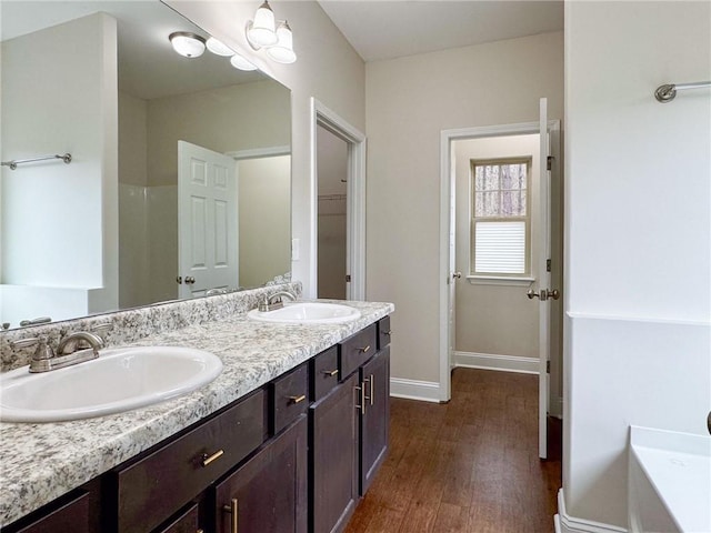 bathroom featuring double vanity, wood finished floors, baseboards, and a sink