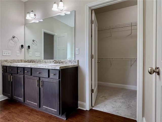 full bath with a spacious closet, double vanity, and a sink