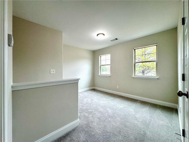 carpeted spare room featuring baseboards and visible vents