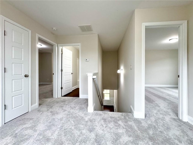 interior space with carpet flooring, an upstairs landing, visible vents, and baseboards