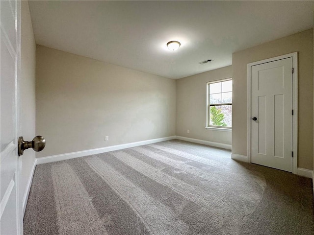 carpeted spare room with visible vents and baseboards