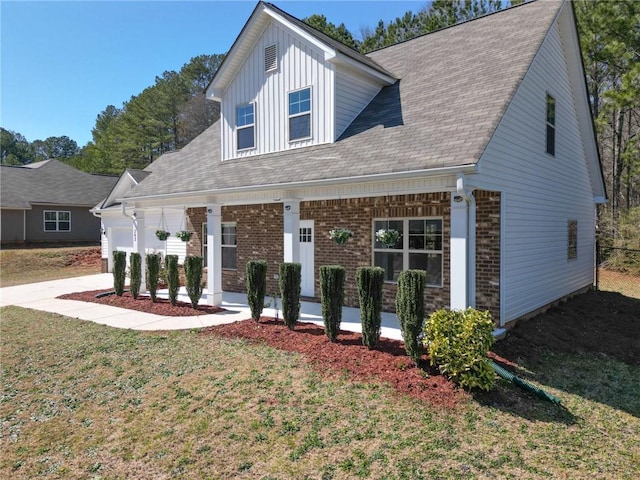 view of front of property featuring a porch, board and batten siding, a front yard, a garage, and brick siding