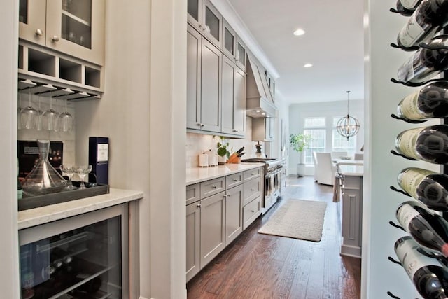 kitchen with premium range hood, decorative light fixtures, beverage cooler, high end stove, and dark hardwood / wood-style floors