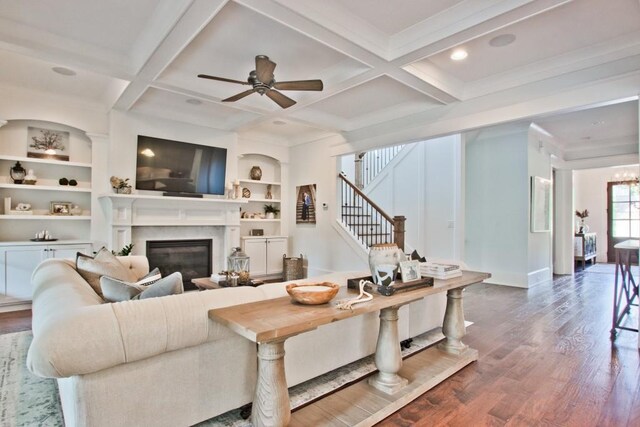 living room featuring coffered ceiling, ceiling fan with notable chandelier, beamed ceiling, and dark hardwood / wood-style flooring