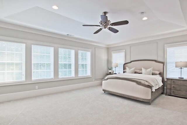 carpeted bedroom with ceiling fan and a tray ceiling