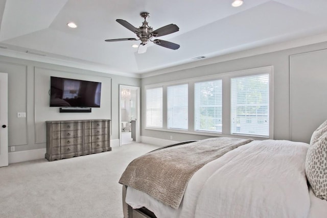 carpeted bedroom with ensuite bath, ceiling fan, and a tray ceiling