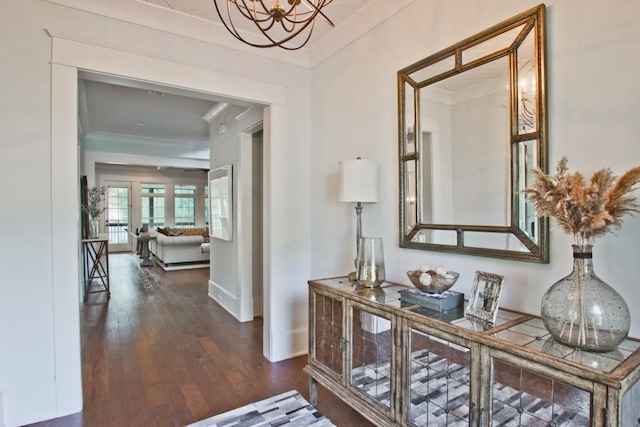 hall with dark hardwood / wood-style floors, an inviting chandelier, and ornamental molding