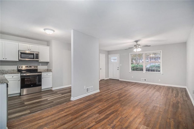 kitchen with appliances with stainless steel finishes, dark hardwood / wood-style floors, white cabinetry, and light stone counters