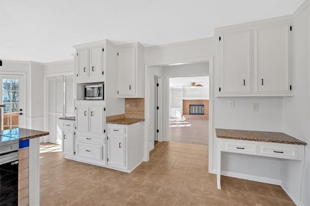 kitchen featuring white cabinetry, stainless steel microwave, a fireplace, and ceiling fan