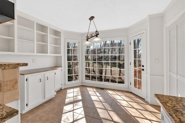 unfurnished dining area with light tile patterned flooring, visible vents, and crown molding