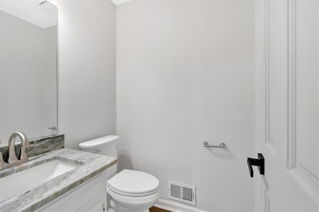 half bath with vanity, toilet, and visible vents