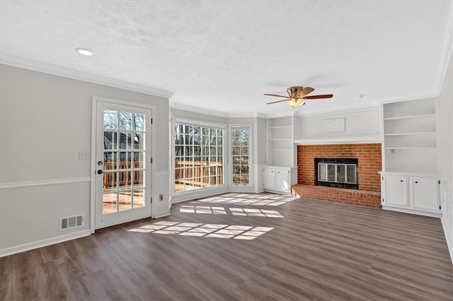 unfurnished living room featuring dark wood-style floors, a brick fireplace, a textured ceiling, and crown molding