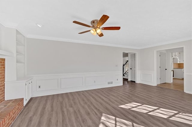 unfurnished living room featuring light wood finished floors, visible vents, ceiling fan, built in features, and ornamental molding