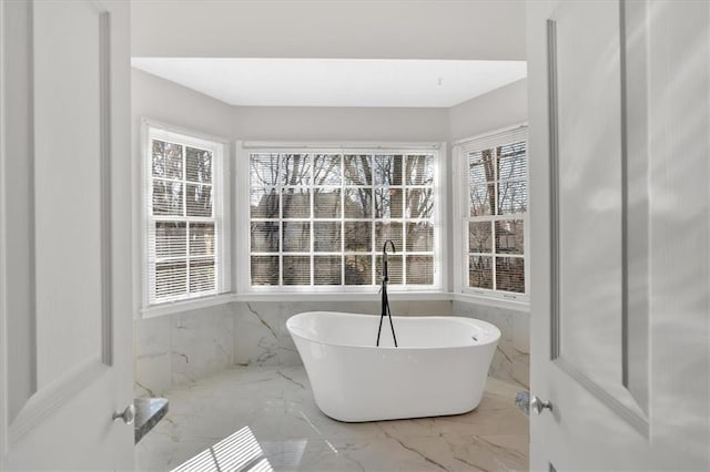 bathroom with a freestanding bath and marble finish floor