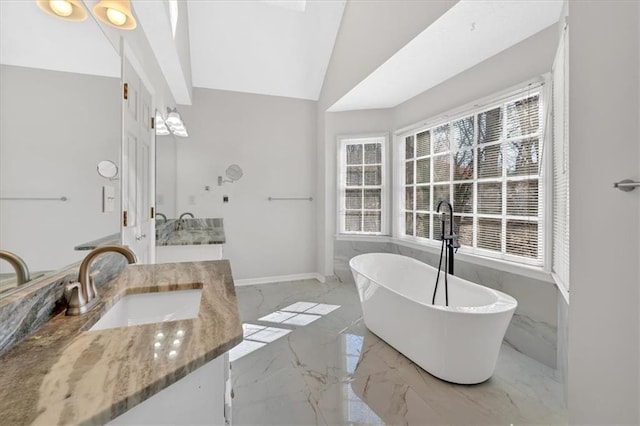 full bathroom featuring baseboards, lofted ceiling, a soaking tub, marble finish floor, and vanity