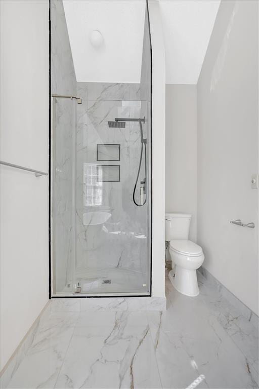 bathroom featuring toilet, marble finish floor, and a marble finish shower