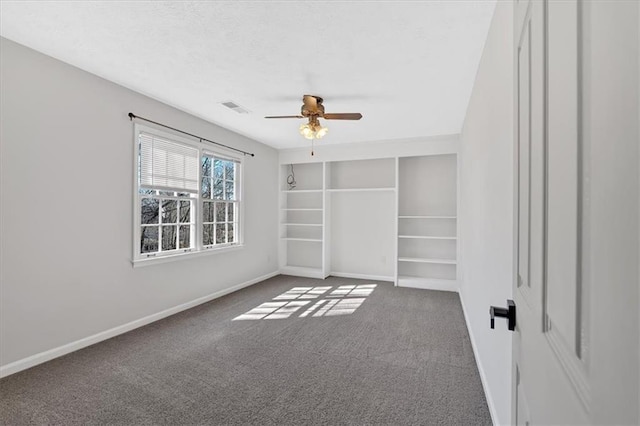 unfurnished bedroom featuring visible vents, a textured ceiling, carpet floors, baseboards, and ceiling fan