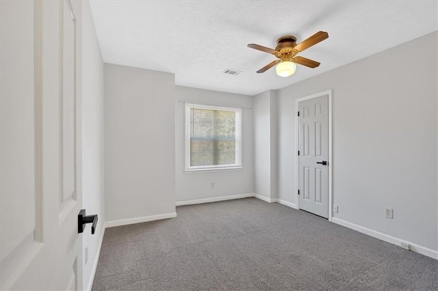 empty room featuring carpet, visible vents, baseboards, ceiling fan, and a textured ceiling