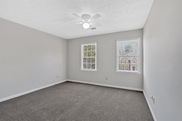 spare room with a textured ceiling, baseboards, dark colored carpet, and ceiling fan