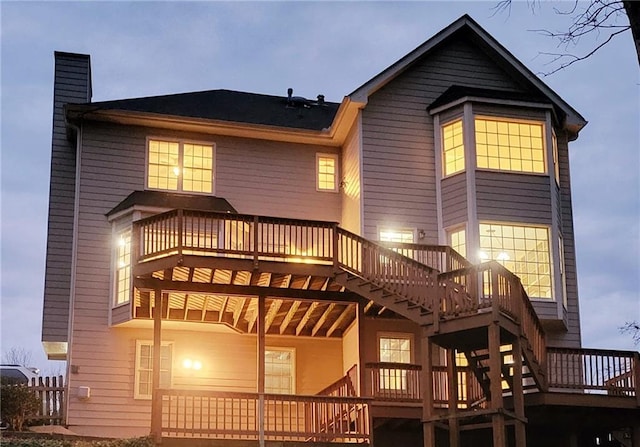 rear view of house with a wooden deck, a chimney, and stairs