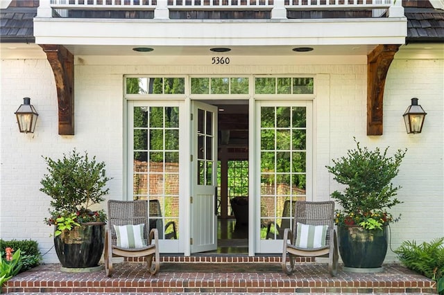 entrance to property featuring brick siding, a balcony, and french doors