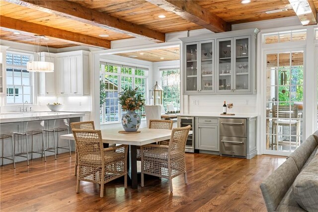dining area with wood ceiling, beamed ceiling, dark wood-type flooring, wine cooler, and healthy amount of natural light
