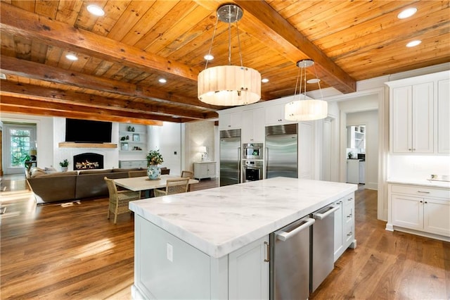 kitchen featuring appliances with stainless steel finishes, wood finished floors, white cabinetry, beamed ceiling, and recessed lighting