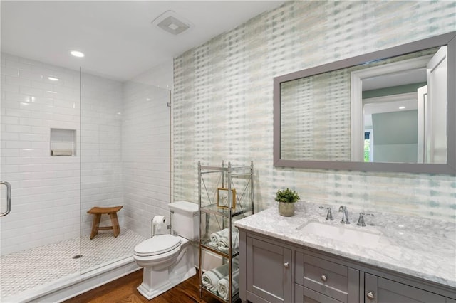 full bath featuring a shower stall, wood finished floors, toilet, vanity, and wallpapered walls