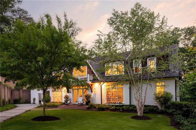 view of front of home featuring a lawn, a balcony, and brick siding