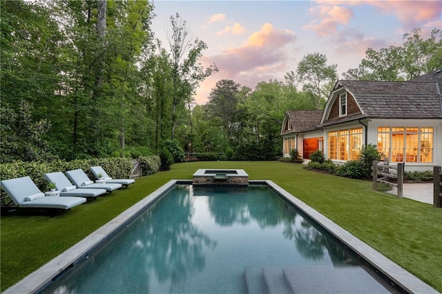 view of pool with a yard, a pool with connected hot tub, and a patio area