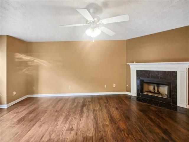 unfurnished living room featuring a tiled fireplace, ceiling fan, hardwood / wood-style floors, and a textured ceiling