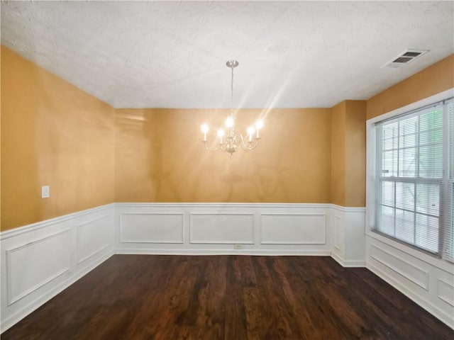 unfurnished dining area featuring dark hardwood / wood-style flooring and a notable chandelier