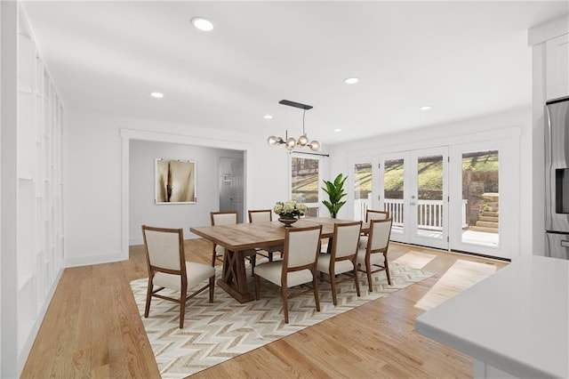 dining room featuring french doors, an inviting chandelier, and light hardwood / wood-style flooring