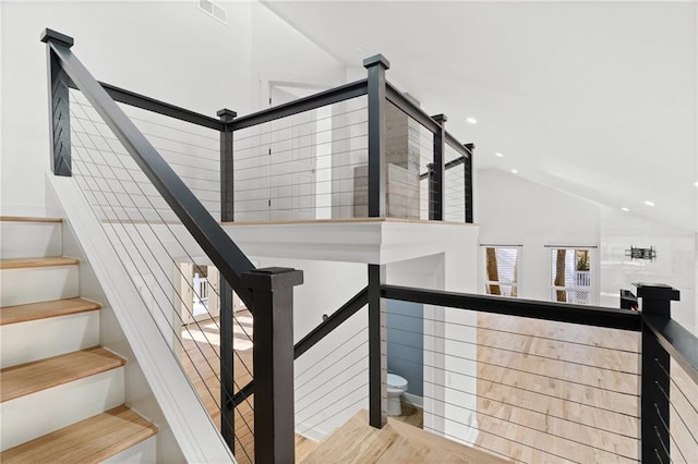 stairway featuring hardwood / wood-style flooring and lofted ceiling