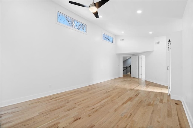 unfurnished living room featuring ceiling fan, a high ceiling, and light hardwood / wood-style floors