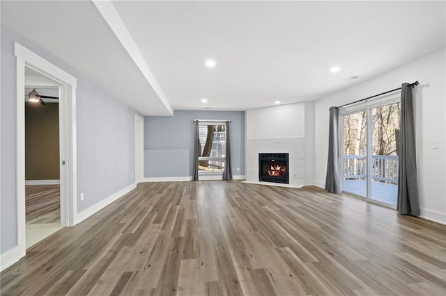 unfurnished living room with a healthy amount of sunlight, a high end fireplace, and light hardwood / wood-style floors