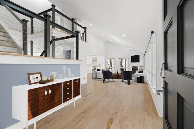 entryway featuring high vaulted ceiling, a large fireplace, and light wood-type flooring