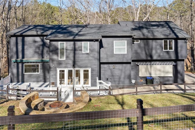 back of property featuring a lawn, a wooden deck, and a fire pit