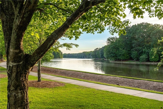 surrounding community with a water view and a lawn