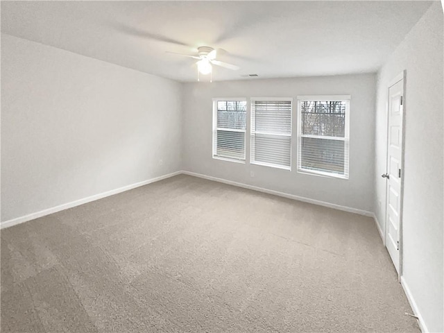 carpeted empty room with ceiling fan, visible vents, and baseboards