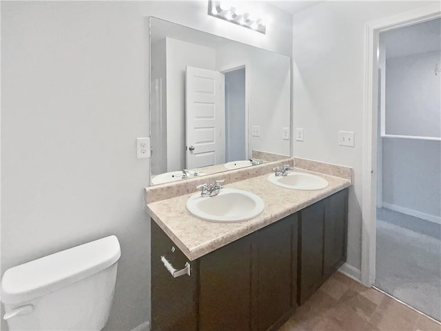 bathroom featuring double vanity, a sink, and toilet