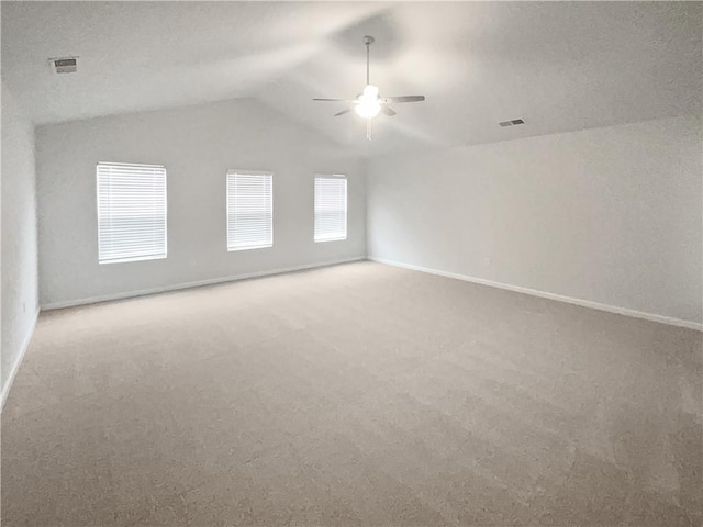 unfurnished room featuring carpet floors, visible vents, vaulted ceiling, and a ceiling fan