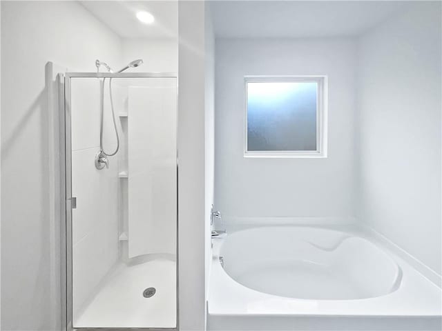 bathroom featuring a stall shower and a bath