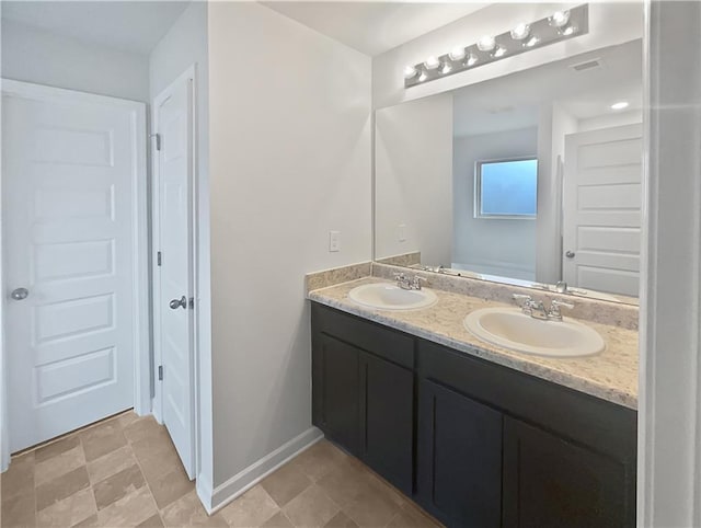 bathroom with double vanity, visible vents, baseboards, and a sink