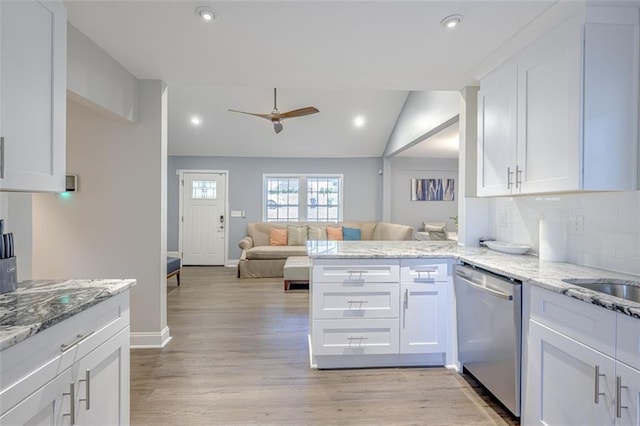 kitchen with kitchen peninsula, stainless steel dishwasher, vaulted ceiling, ceiling fan, and white cabinetry