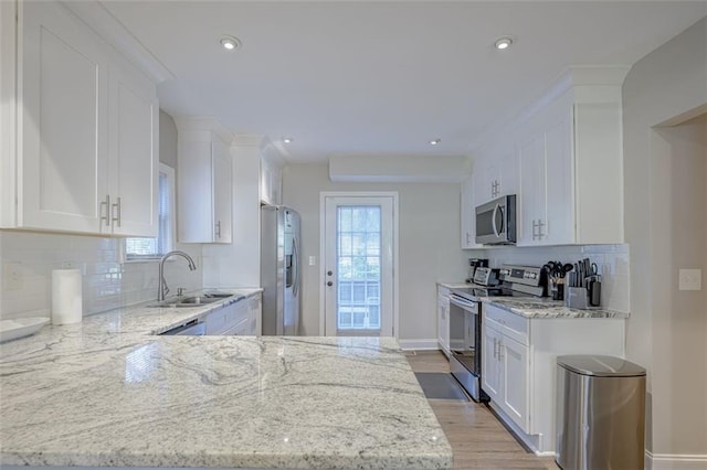 kitchen featuring white cabinets, sink, tasteful backsplash, light stone counters, and stainless steel appliances