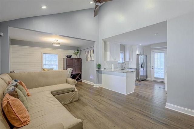 living room with light hardwood / wood-style floors, ceiling fan, lofted ceiling, and sink