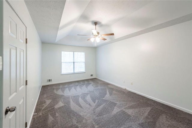 unfurnished room featuring a textured ceiling, ceiling fan, a tray ceiling, and carpet