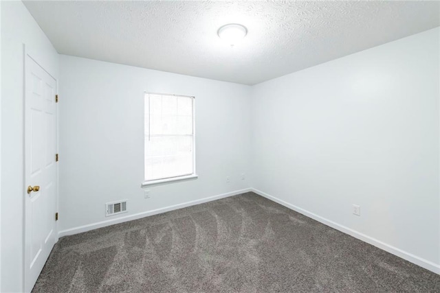 spare room with dark carpet and a textured ceiling