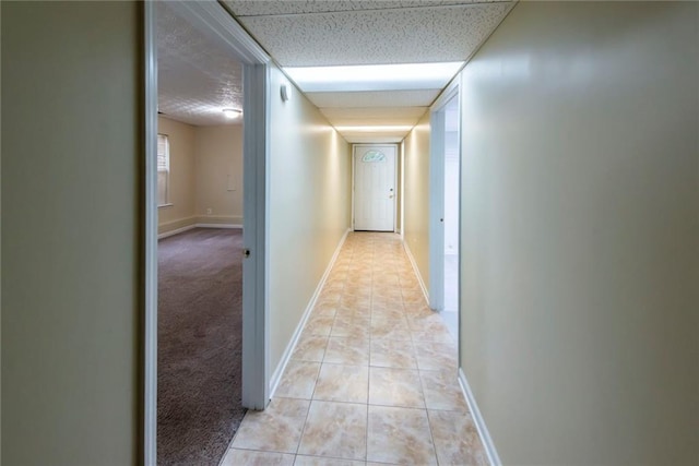 corridor featuring a paneled ceiling and light tile patterned floors